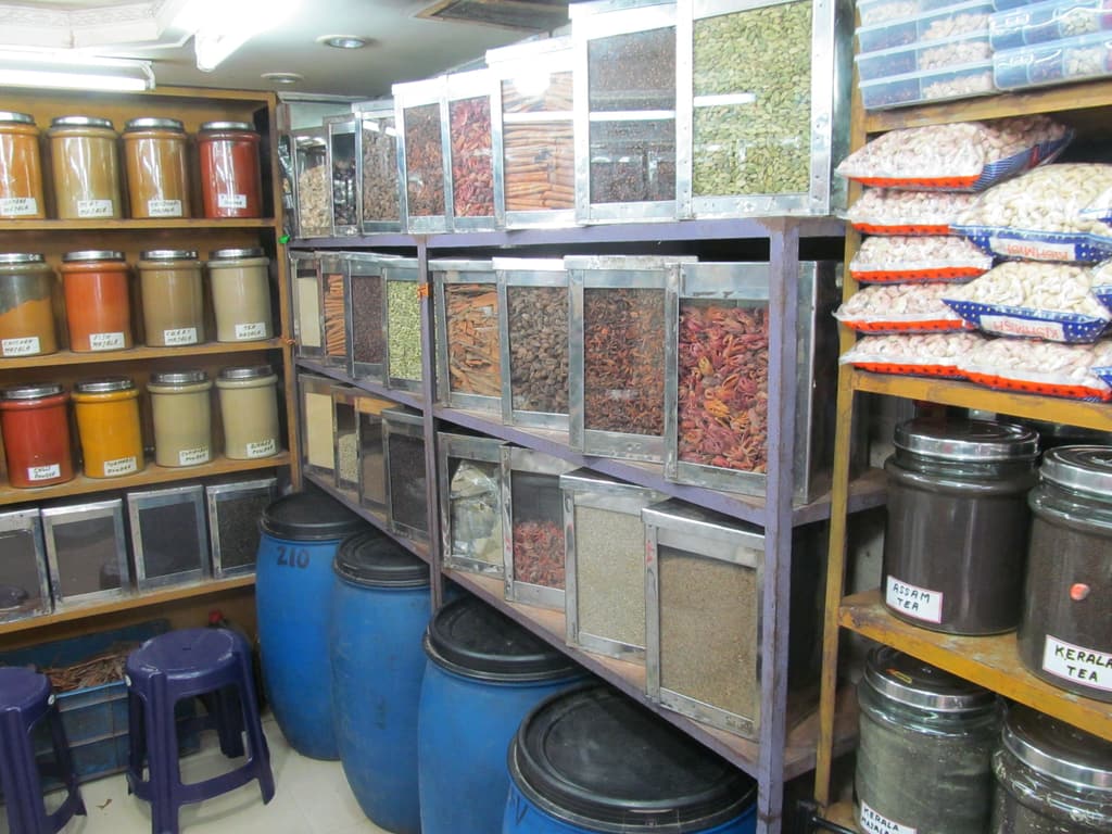 Inside an Indian provision store: spice jars, grain bins and sacks of rice on steel shelves